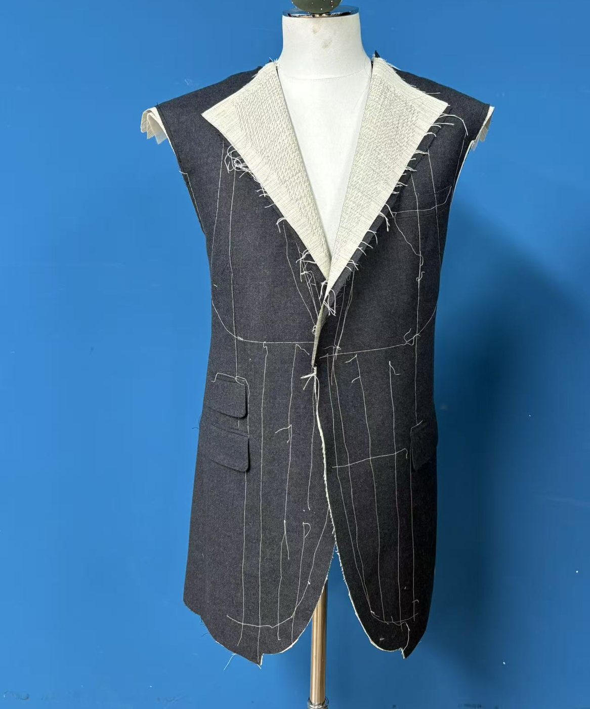 A full-canvas front panel in grey wool, the lapel and collar canvas showing a small, even, regularly repeating diagonal machine stitch